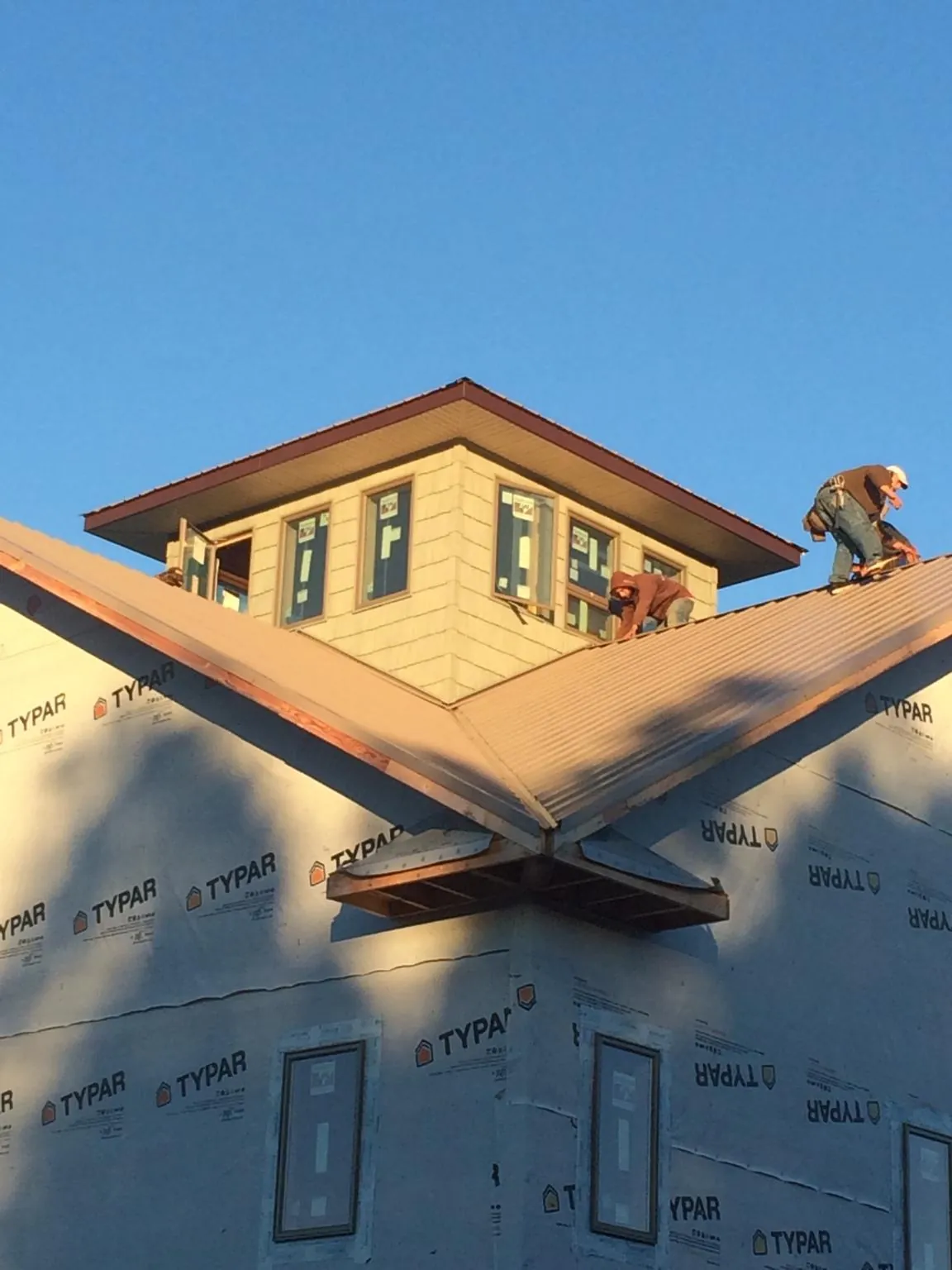 Roofers working around a rooftop cupola on a new metal roof at sunset — Roof Waterproofing in Liverpool by Roofing Brothers